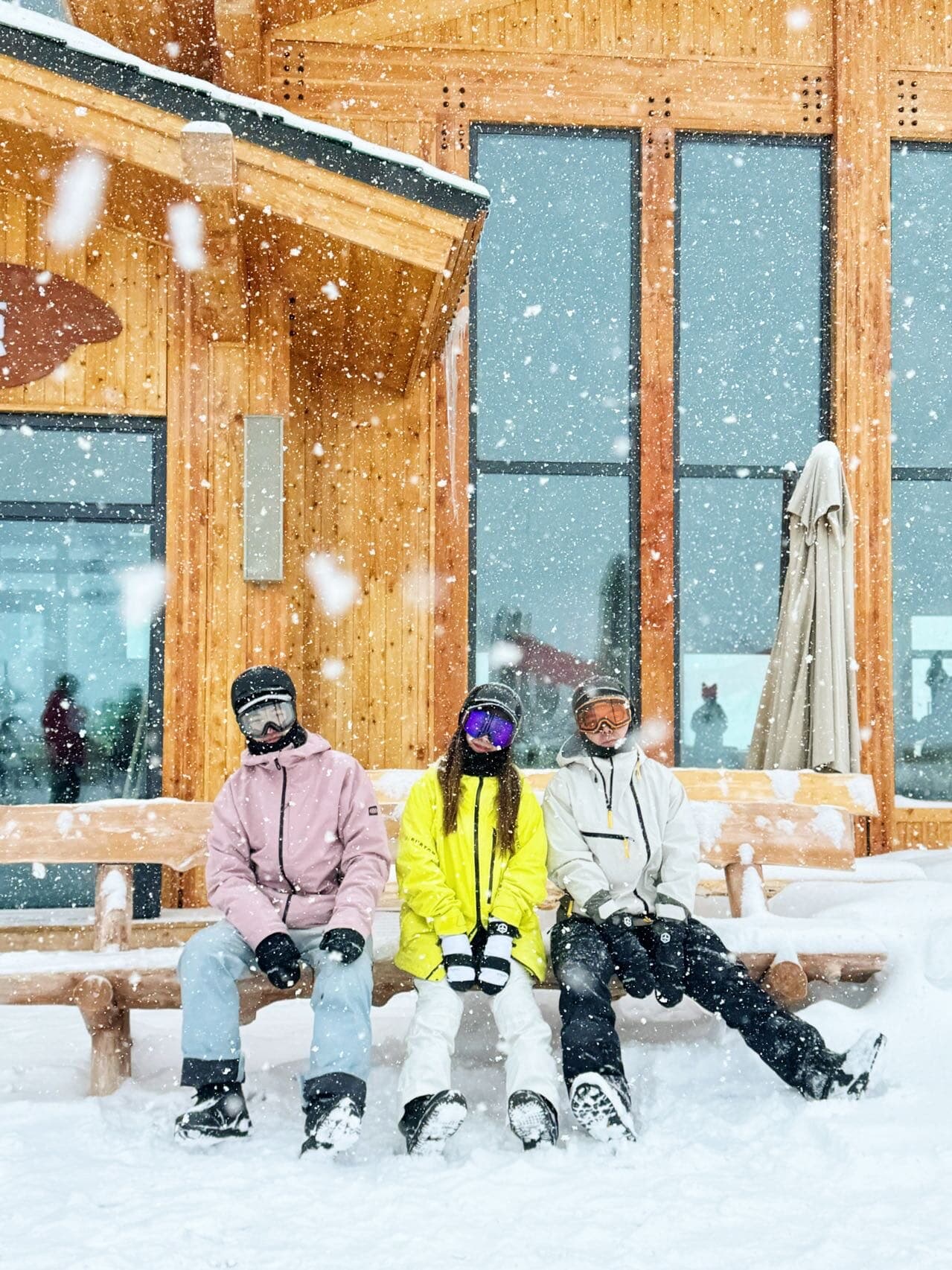 Friends resting on a lodge bench in the snowfall