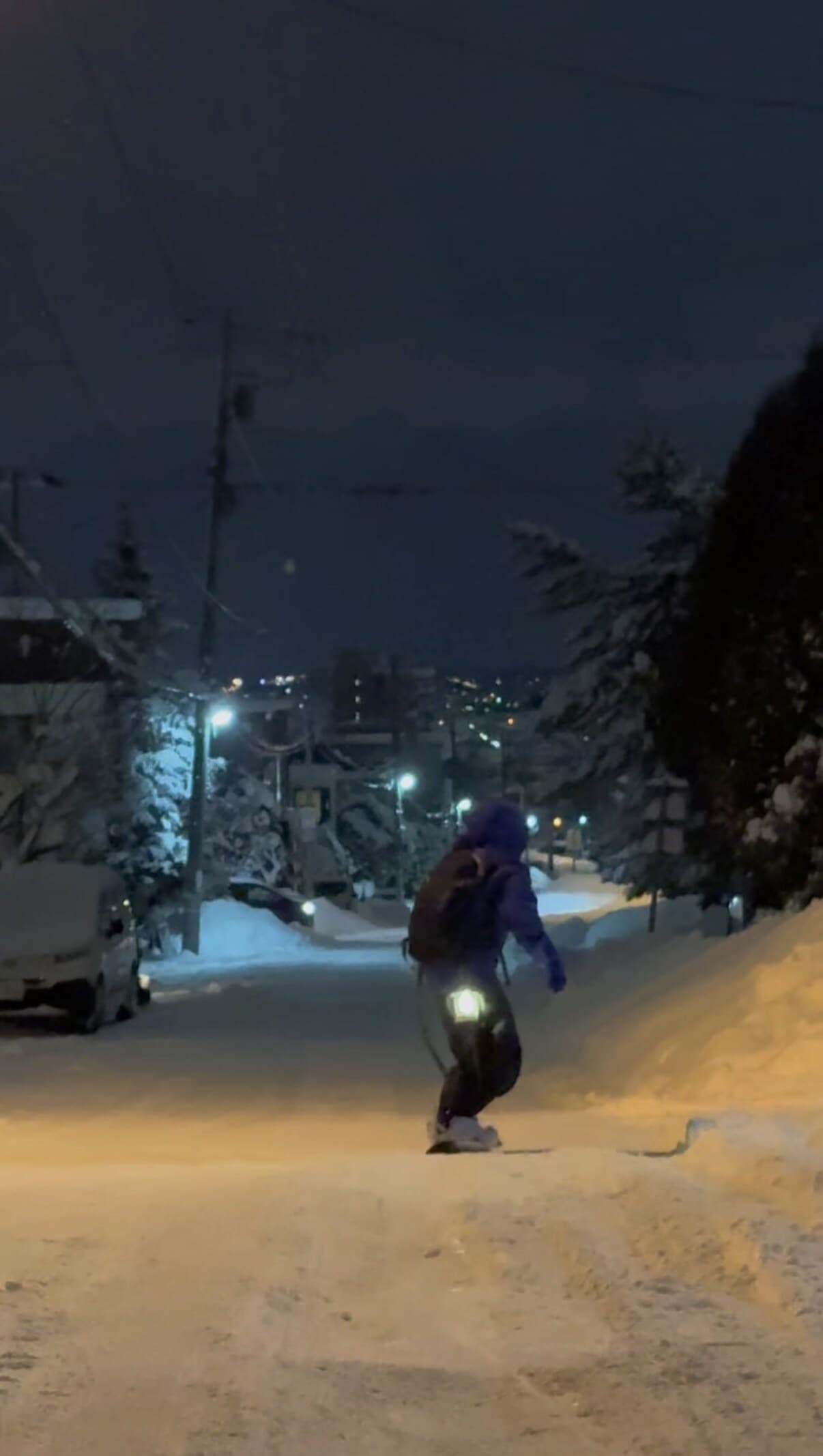 Snowboarder on a snowy Sapporo street at night