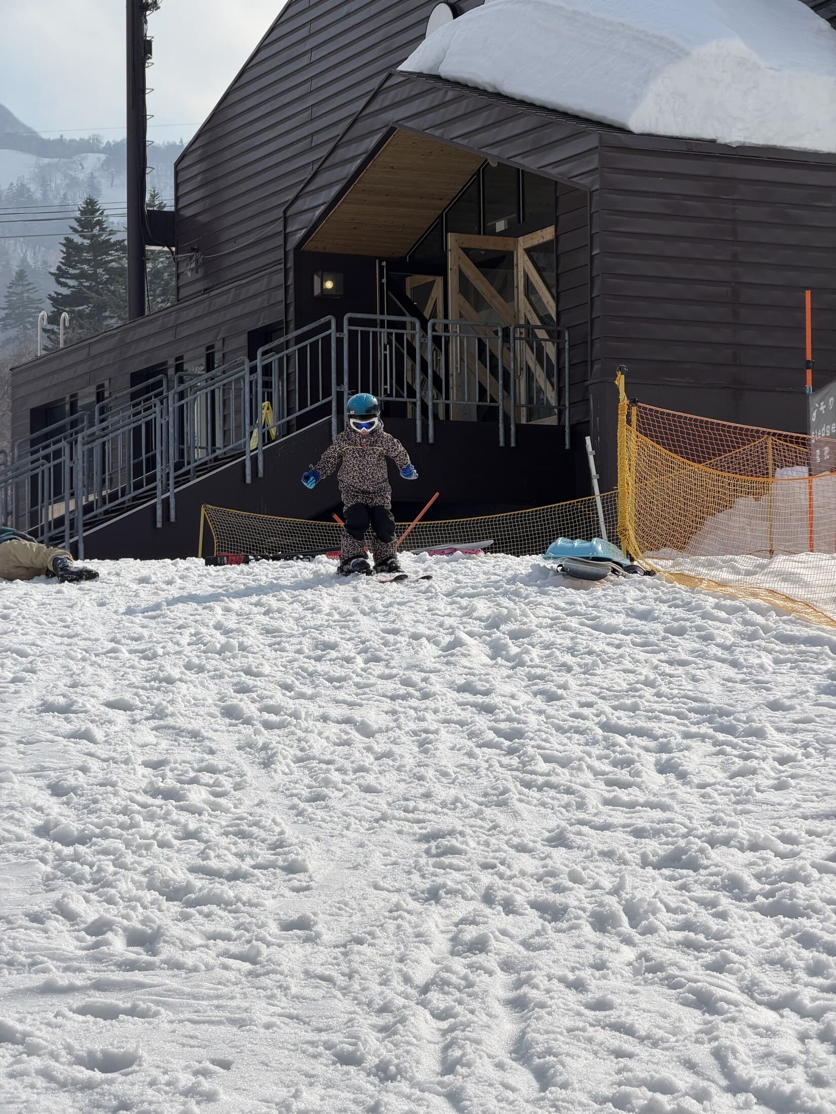 Child learning to ski near the lodge